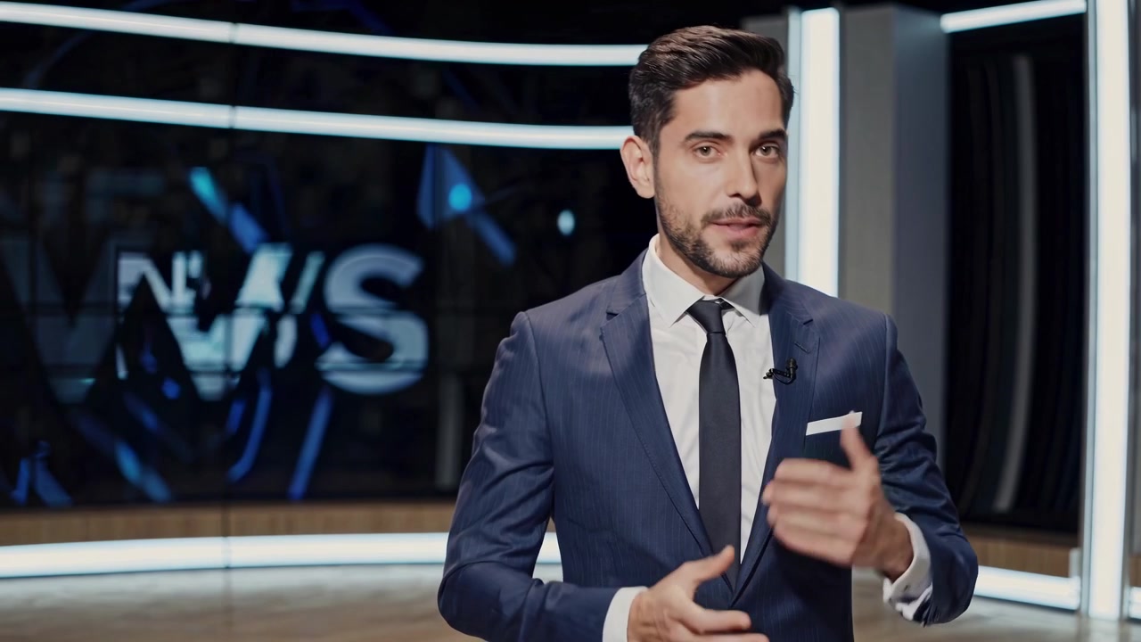 Conduttore di telegiornale che parla e gesticola in un moderno studio televisivo