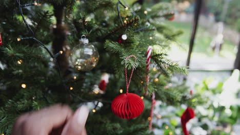 close up of man hanging decoration on christmas tree at home