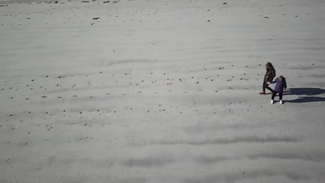 Vista-Lateral-Aérea-De-Dos-Personas-Caminando-Sobre-La-Arena-En-Una-Gran-Playa-Irlandesa