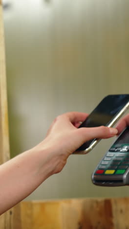 woman paying bill through smartphone using nfc technology