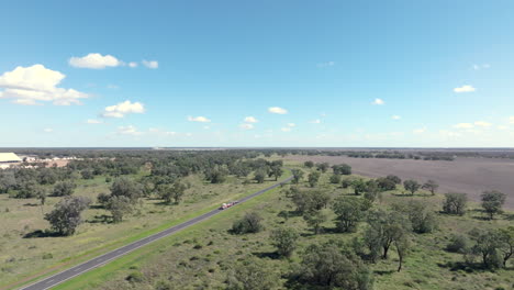 an empty road train driving past cotton fields towards moree, new south wales, australia