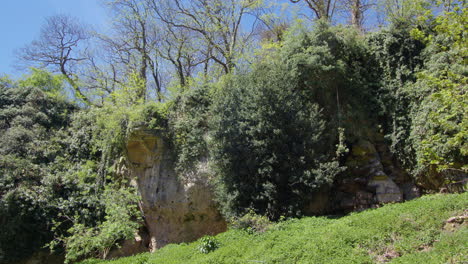 Wide-mid-shot-of-limestone-overhang-at-limestone-gorge-with-vegetation,-Creswell-Crags