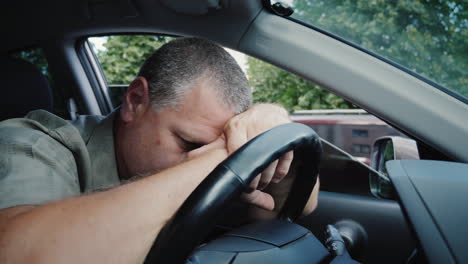 tired middle-aged man put his head on the wheel of a car