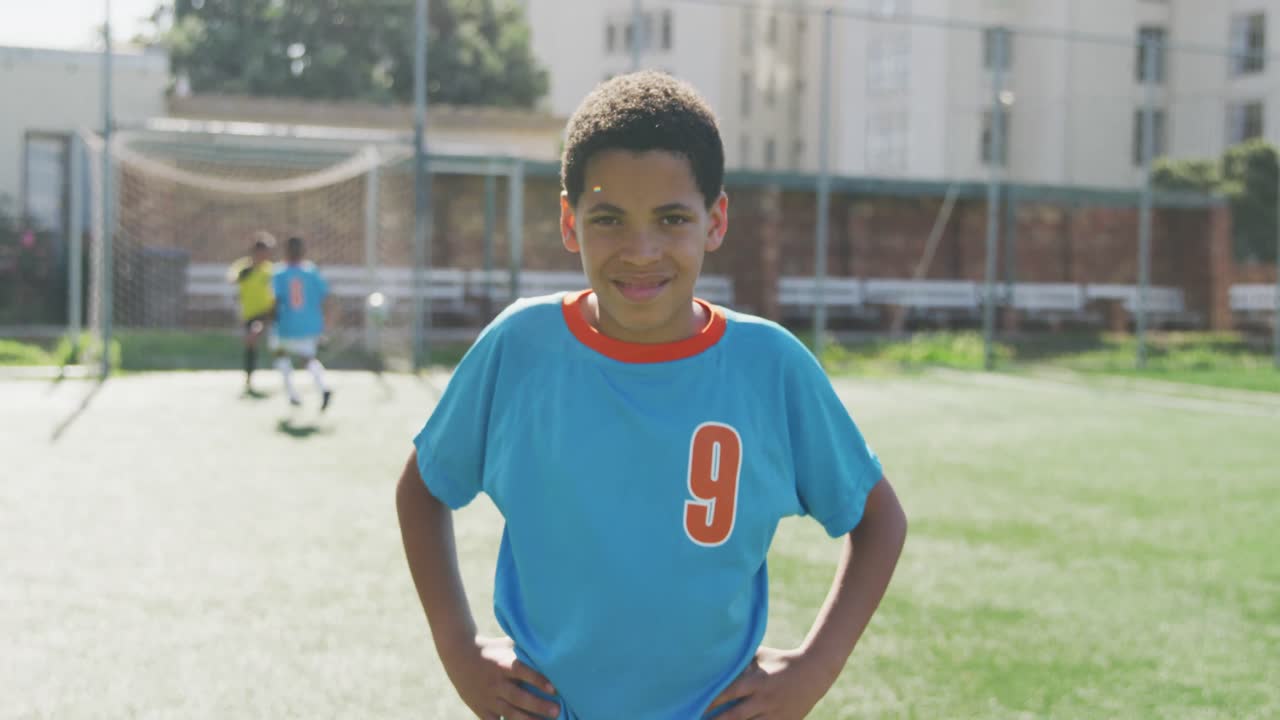 African American soccer kid in blue smiling and looking at camera