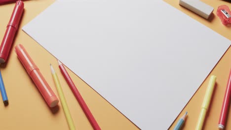 close up of blank sheet of paper with school stationery on beige background, in slow motion