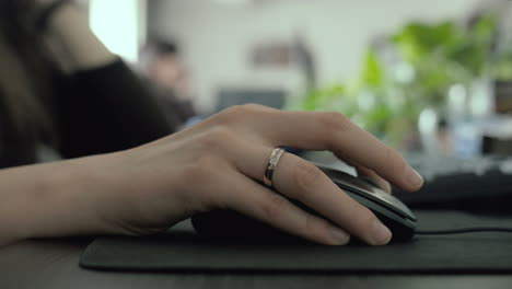 close up shot as a female hand with wedding ring using a mouse in the office