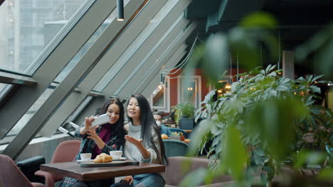 two women taking a selfie in a modern cafe