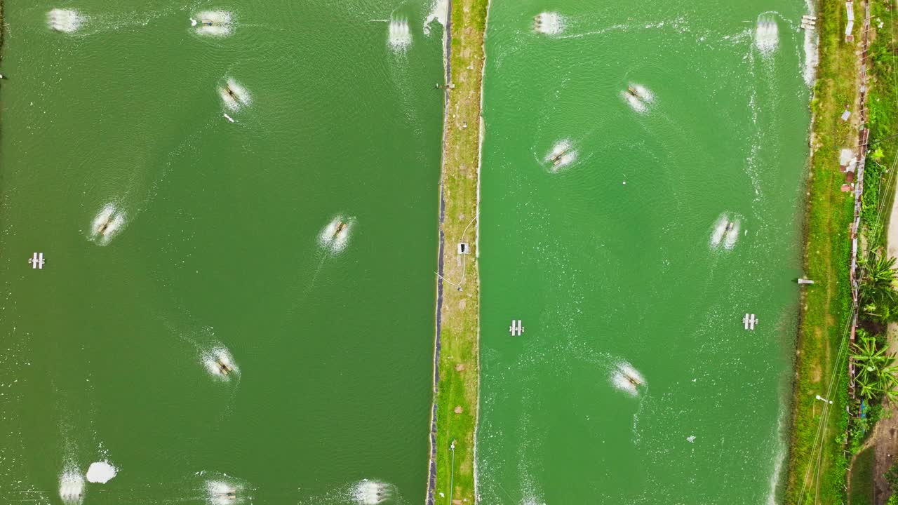 Drone descends over fish and shrimp ponds showing oxygen aeration system