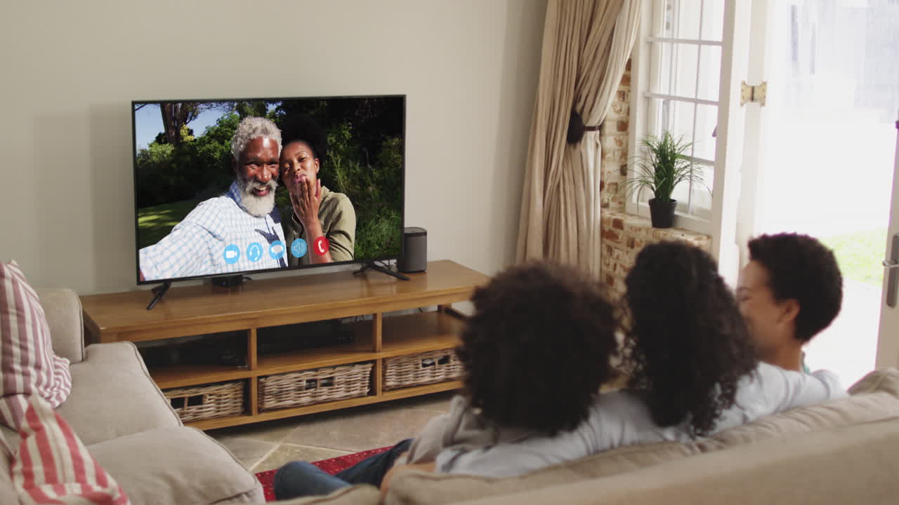 아프리카계 미국인 가족 이 집 에서 소파 에 앉아 tv 에서 비디오 통화 를 하고 있다