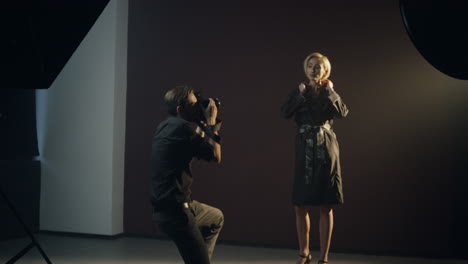 joven modelo caucásica posando en el estudio oscuro mientras el fotógrafo tomaba fotos de ella