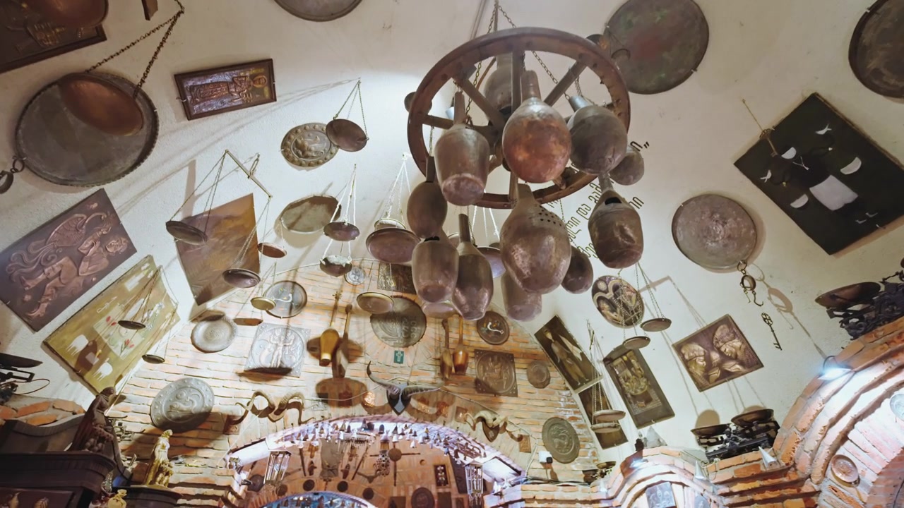 Old copper scales, trays and framed pictures hang from the whitewashed brick vault of an underground bazaar in Tbilisi.
