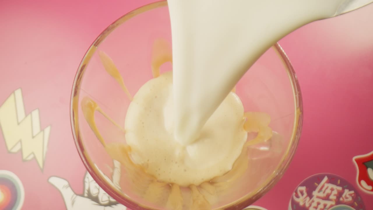 Vanilyalı dondurmanın üzerine buharda ısıtılmış sıcak süt dökülüyor, üstten görünüm. Milkshake