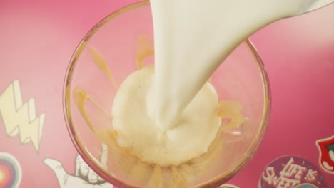 pouring steamed hot milk over vanilla ice cream top view milkshake