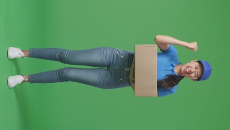 full body of asian female courier in blue uniform celebrating succeed delivering a carton on green screen background in the studio