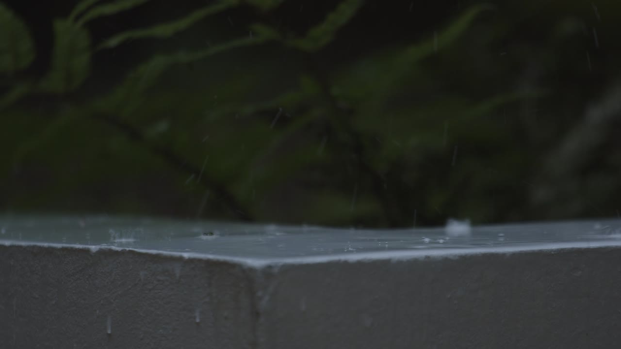 Raindrops hitting the ledge in close up