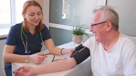 zoom in shot of young male therapist in white coat measuring blood pressure of senior patient in ward of clinic