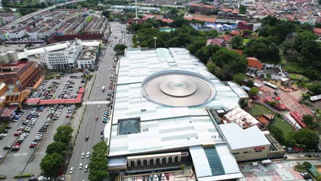 rotating aerial shot around the busy melaka megamall with traffic passing by