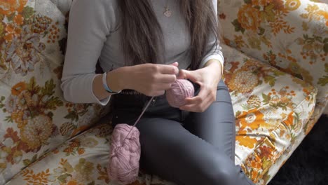 vista de ángulo medio alto de una mujer organizando hilo rosado en una bola envuelta de bobina