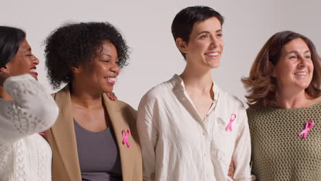 Close-Up-Studio-Portrait-Of-Smiling-Multi-Racial-Group-Of-Women-Of-Different-Ages-Wearing-Pink-Breast-Cancer-Awareness-Ribbons