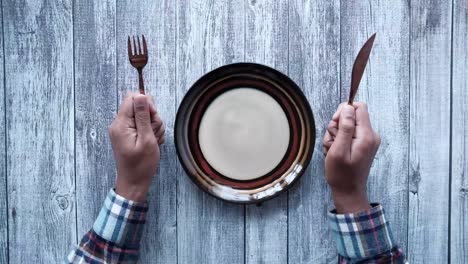 empty plate with fork and knife on a wooden table