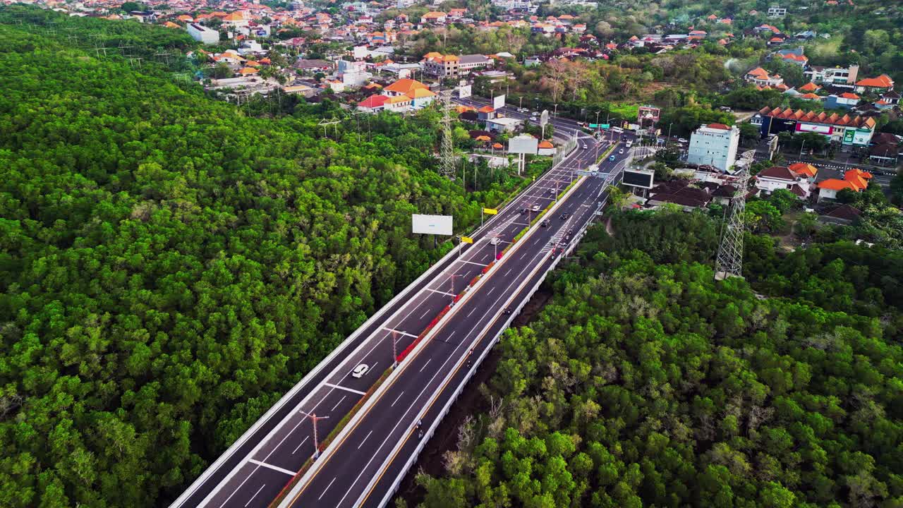 Aerial view highlights a modern bridge cutting through dense mangrove forest with traffic flowing across the street showing the balance between transportation design and natural tropical greenery