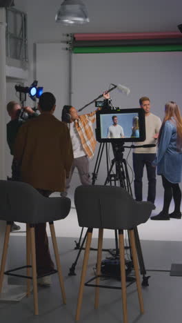video vertical de una directora caminando hacia un set de cine ocupado con el equipo de rodaje de la película en el estudio para hablar con los actores