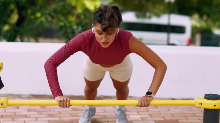 Wanita Muda Melakukan Push-up di Peralatan Kebugaran Luar Ruangan