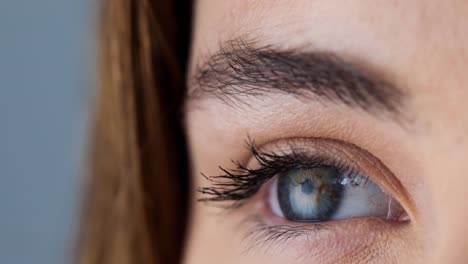 Close-up-of-female-brown-eye-against-grey-background