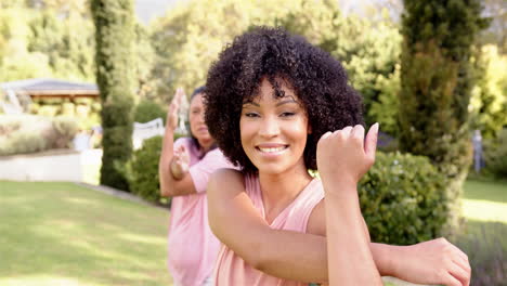 stretching arms outdoors, smiling woman enjoying fitness routine with friend