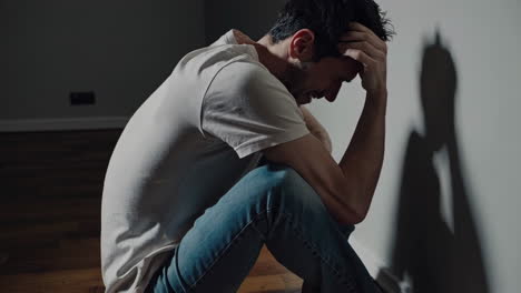 man sitting alone crying against the wall