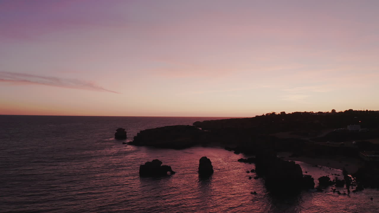 majestuosa toma aérea hacia atrás de rocas sobresalientes del océano y la costa después del atardecer