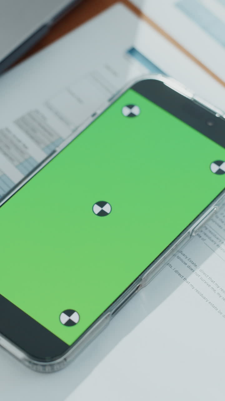 Smartphone con schermo verde sulla scrivania dell'ufficio con documenti