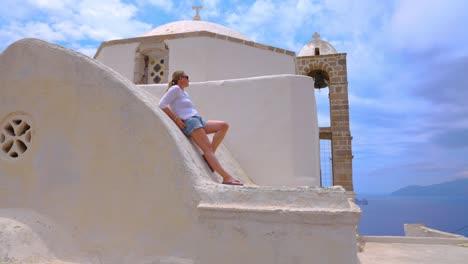 female traveler relaxing on greek church architecture on the greek island of milos, greece