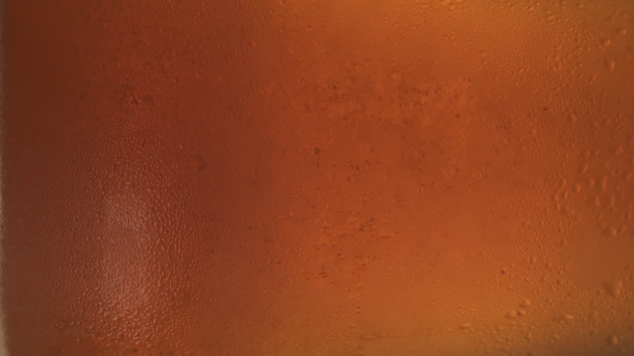 primo piano di un bicchiere rotante con birra frizzante fredda