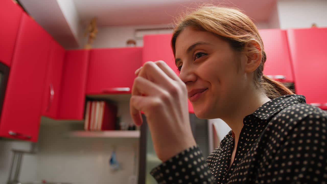 Woman Tastes Tea In A Glass And Smiles In Her Kitchen