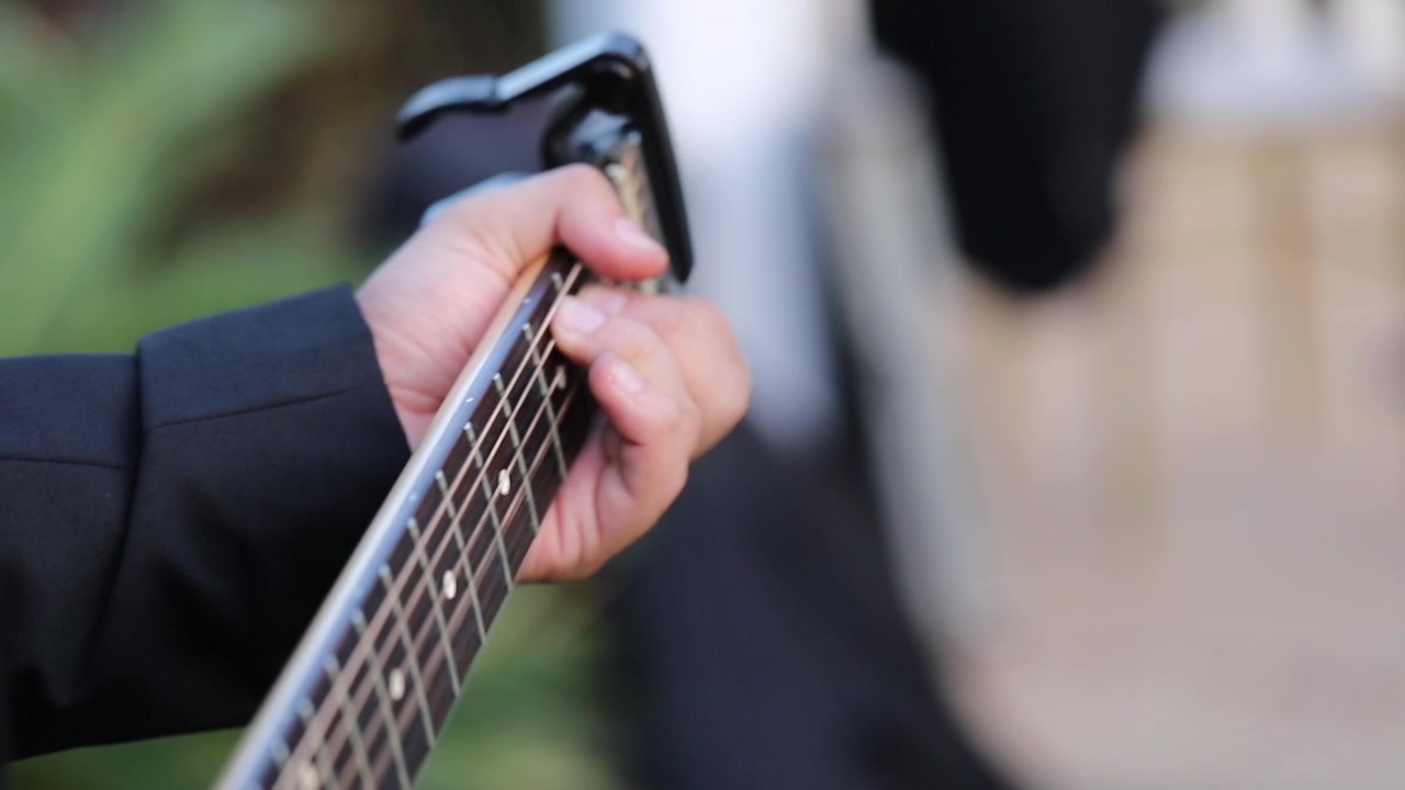 A young man plays the guitar at a wedding - close up