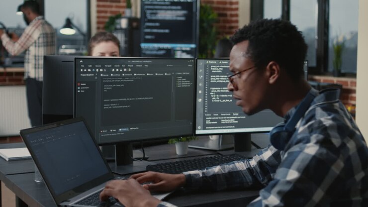 Ritratto di un programmatore che si sistema gli occhiali mentre digita al computer, soddisfatto dei risultati di compilazione seduto alla scrivania