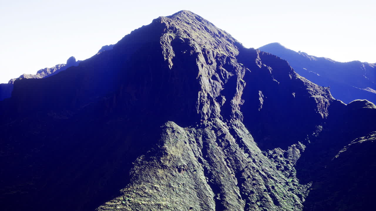 Majestic mountain peak rises above lush valley in bright daylight