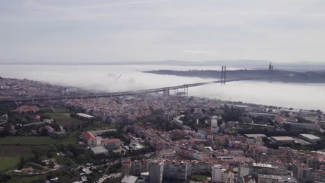 Establish-scenic-bridge-in-Lisbon-covered-in-moody-clouds,-aerial-skyline