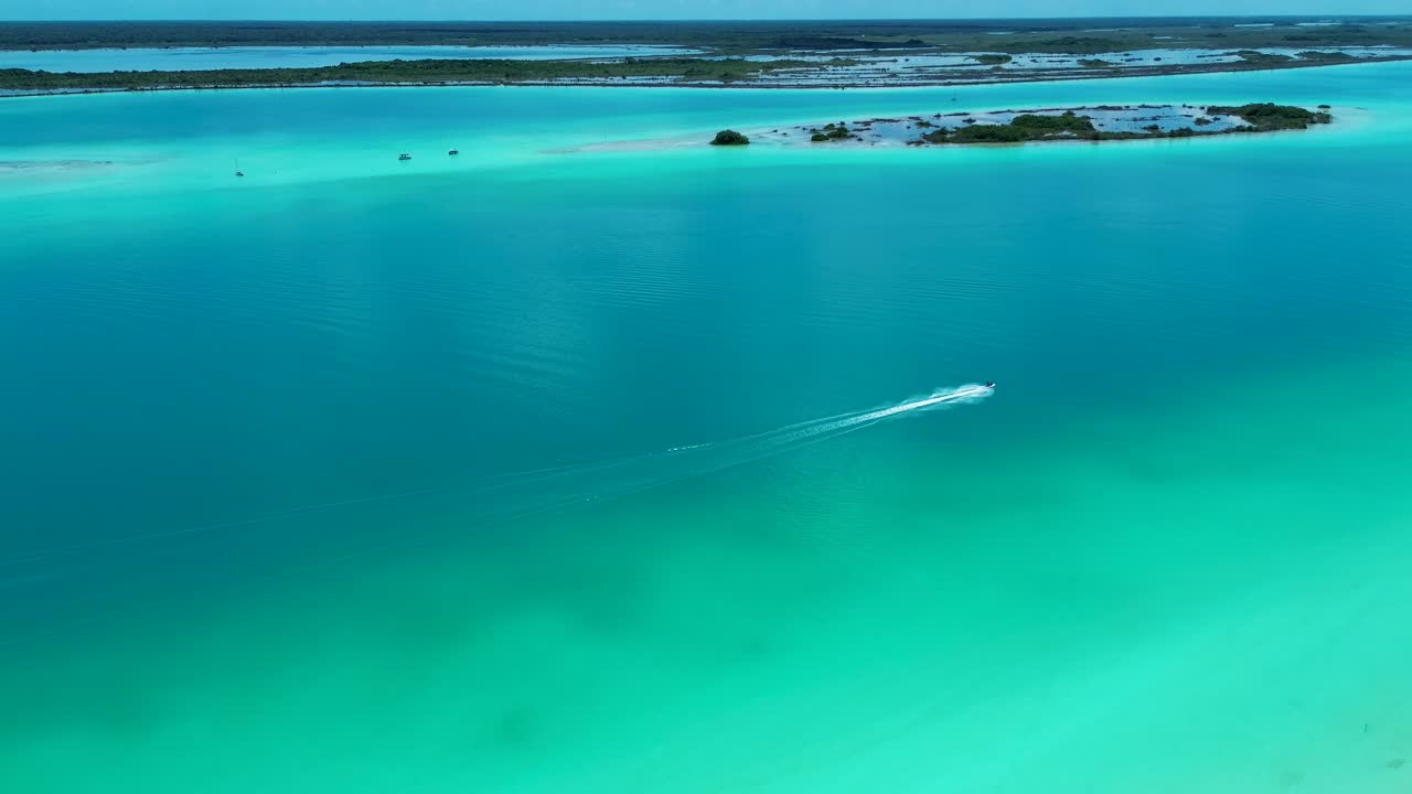 Drone aerial of jet ski water sports boat motor driving across Bacalar lagoon lake river sandbar Quintana Roo nature travel tourism holidays inlet channel Mexico Central America