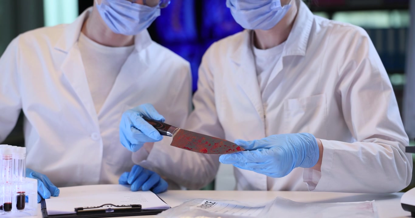 Women assistants take bloody knife out of plastic bag in lab