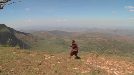 a masai warrior walking along a vast landscape in northern kenya