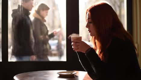 a contemplative moment: a young woman gazing out at the bustling street while savoring her coffee in a cozy café setting