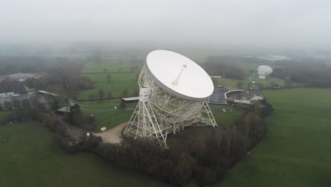 Aerial-Jodrell-bank-observatory-Lovell-telescope-misty-rural-countryside-pull-back-orbit-left