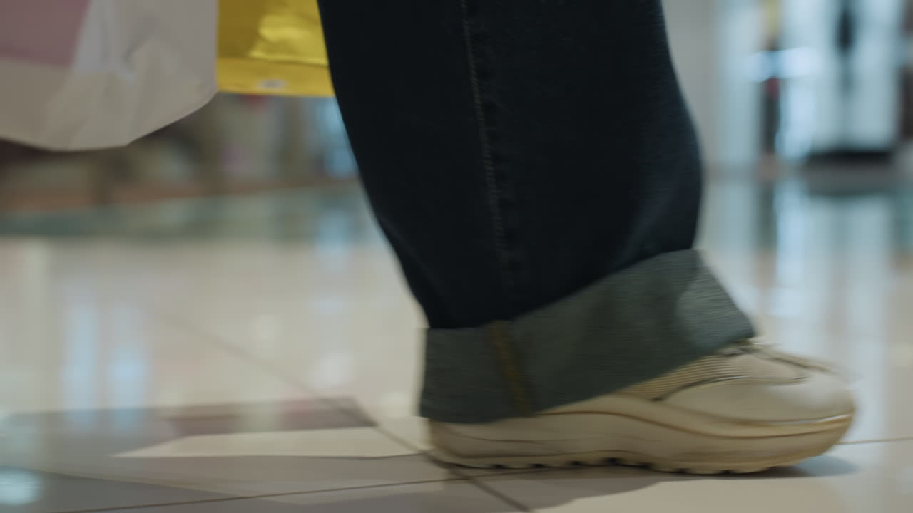 반사되는 쇼핑객들의 모습, 번화한 쇼핑 센터를 거닐고, 쇼핑백을 든 방문객들의 발길이 반짝이는 바닥과 활기찬 인파로 가득한 활기 넘치는 쇼핑몰을 가로지르고 있어요.