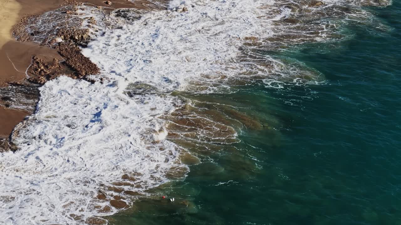 Le onde si infrangono sulla spiaggia sabbiosa di Lanzarote, Spagna, sotto un sole splendente