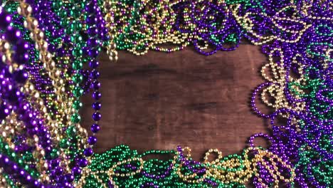 flat lay border of colorful mardi gras beads with more beads hanging on side moving slightly