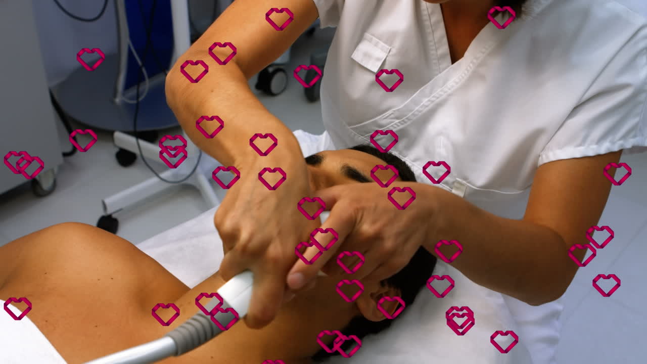 animación de corazones flotando sobre un paciente masculino biracial y una doctora durante el tratamiento con láser