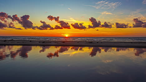 El-Agua-Del-Canal-Refleja-Una-Colorida-Puesta-De-Sol-Sobre-Una-Playa-Junto-Al-Mar---Time-Lapse-Dorado