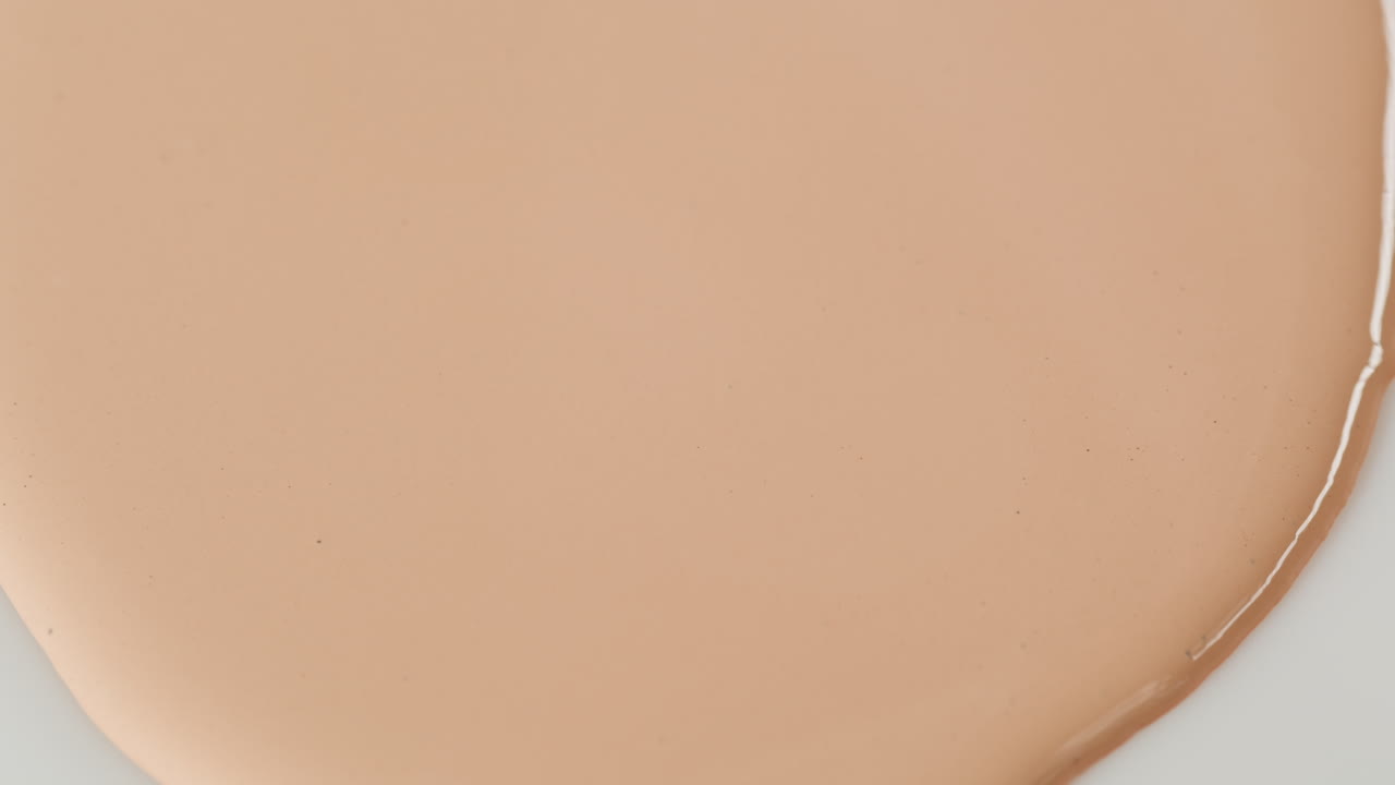 Fondotinta cosmetico beige che si diffonde su una superficie bianca